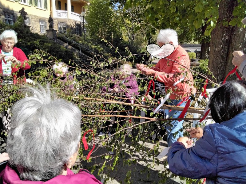 Bewohnerinnen und Bewohner schmücken den Maibaum im Haus Mainblick