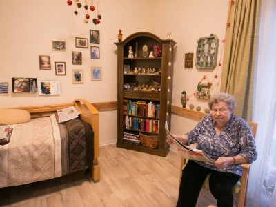 Eine Frau sitzt in einem Zimmer des Seniorenhauses Mühlenpark und Zeitung.