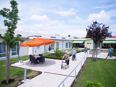 Senioren genießen einen Spaziergang im Garten des Seniorenhauses Mühlenpark