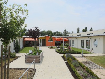 Ein Garten mit Blumen und Sitzbereichen umgibt das Seniorenhaus Mühlenpark