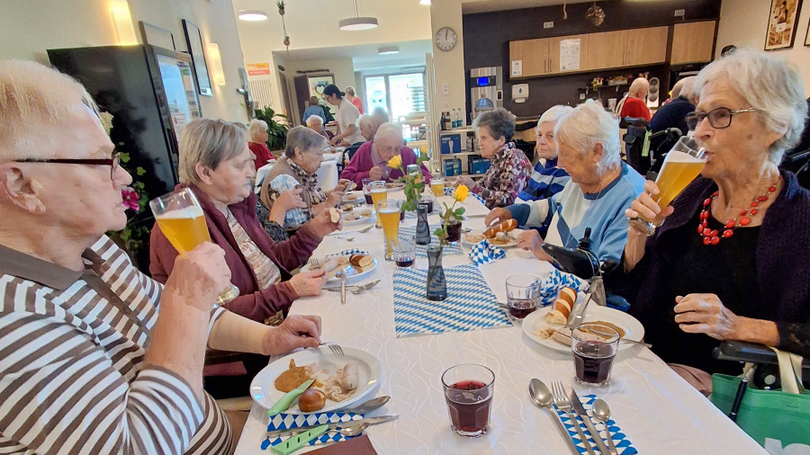 Senioren genießen Oktoberfest mit Bier und traditionellen Speisen.