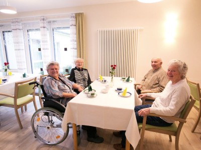 Eine Gruppe Menschen sitzt am Tisch und genießt ihre Zeit im Mühlenpark.